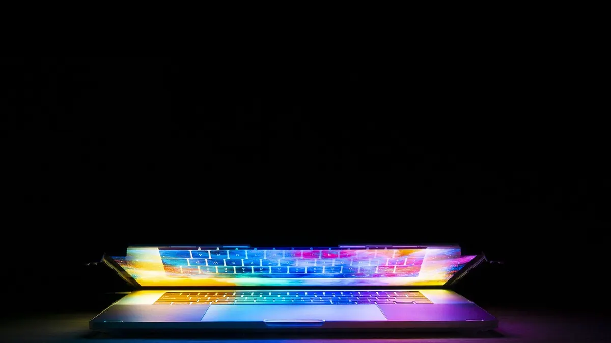 Laptop z projektem logo firmy i szkicownik na biurku