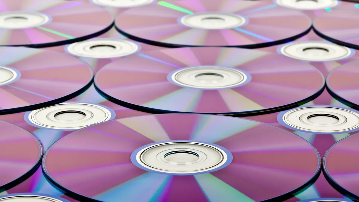 Płyta DVD i zewnętrzny napęd optyczny obok laptopa
