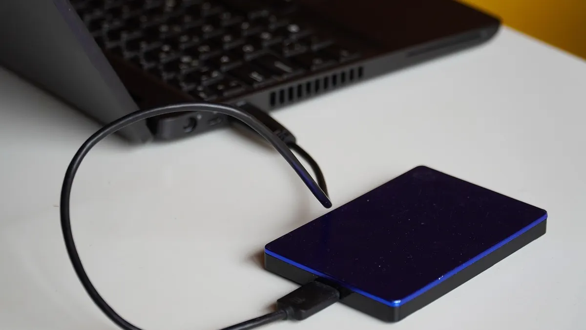 Laptop z folderami plików i podłączonym dyskiem zewnętrznym do tworzenia kopii danych