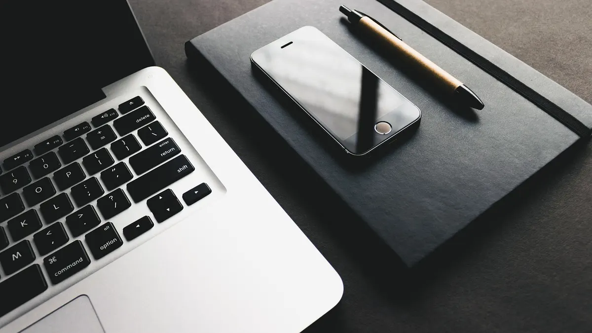 MacBook z widoczną klawiaturą i przyciskiem zasilania na biurku