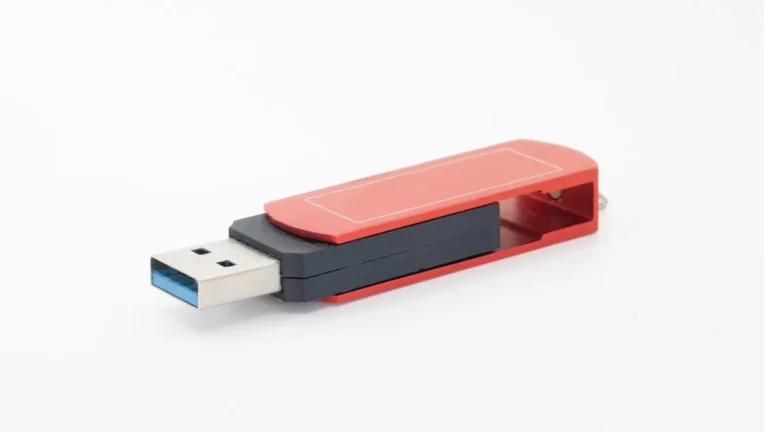 Laptop z pendrivem USB przygotowany do instalacji Linux Mint obok Windows 10