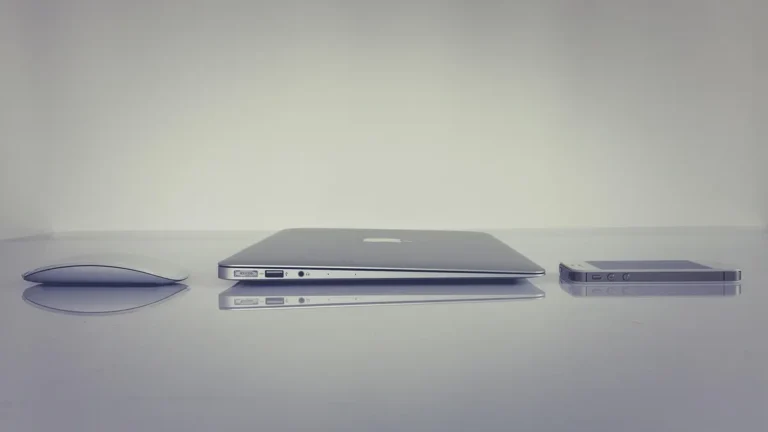 iPhone podłączony kablem USB do MacBooka podczas przenoszenia zdjęć