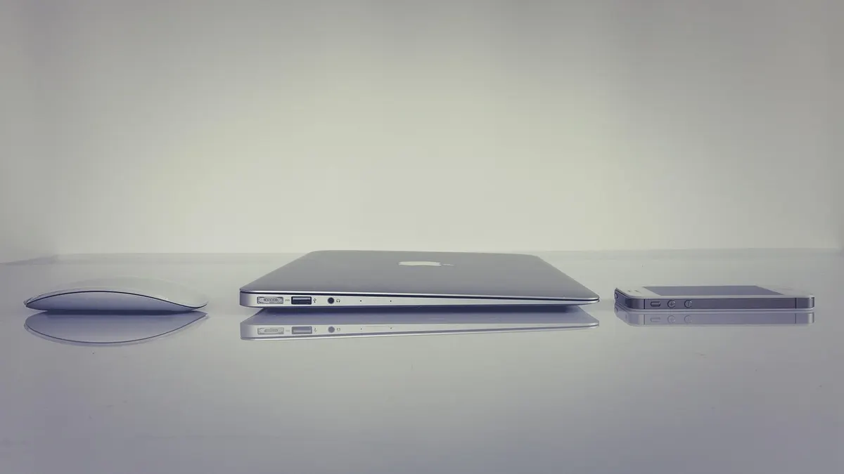 iPhone podłączony kablem USB do MacBooka podczas przenoszenia zdjęć