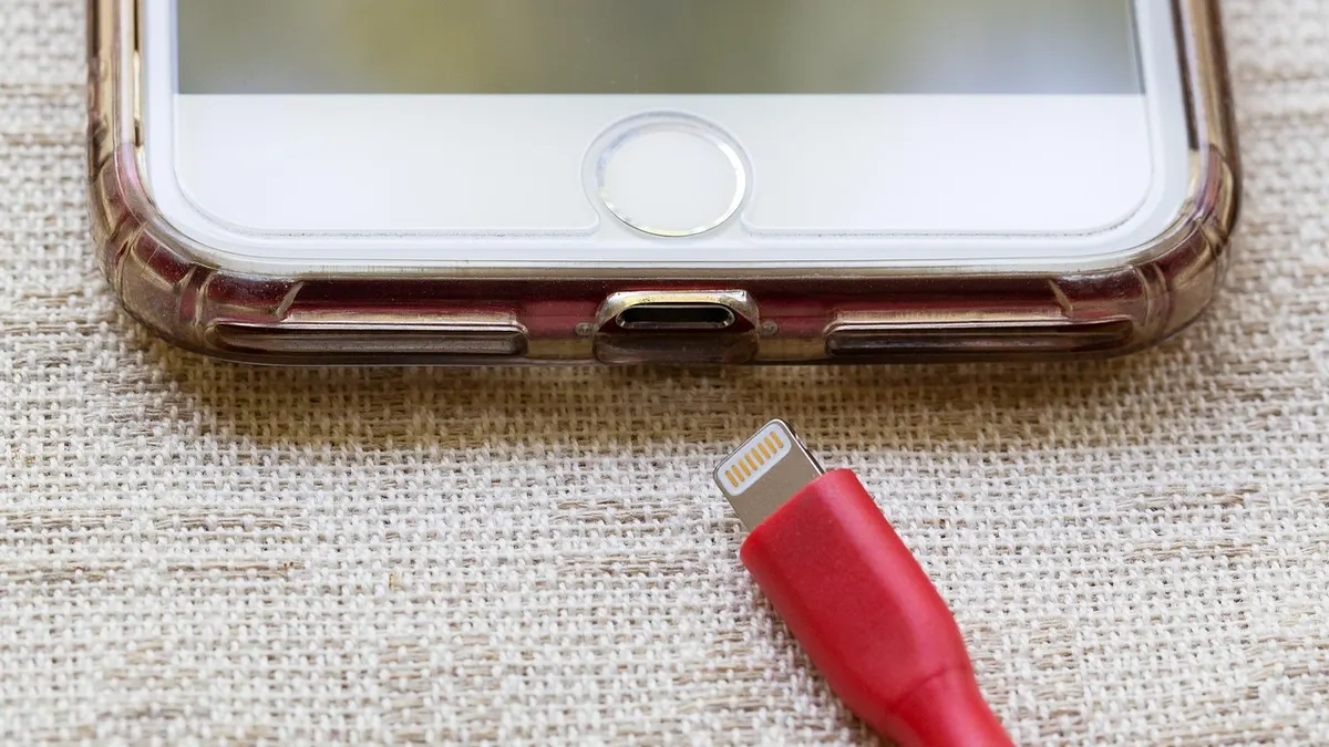 iPhone podłączony kablem USB do laptopa podczas synchronizacji zdjęć
