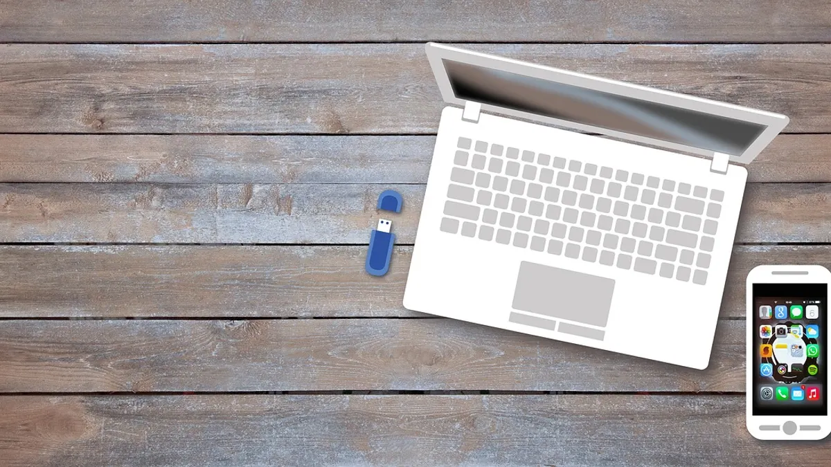 Laptop z telefonem, kablem USB i pendrivem podczas kopiowania zdjęć