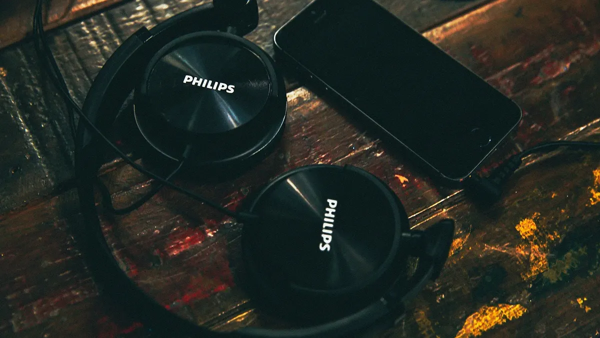 Słuchawki obok smartfona i laptopa z plikami audio